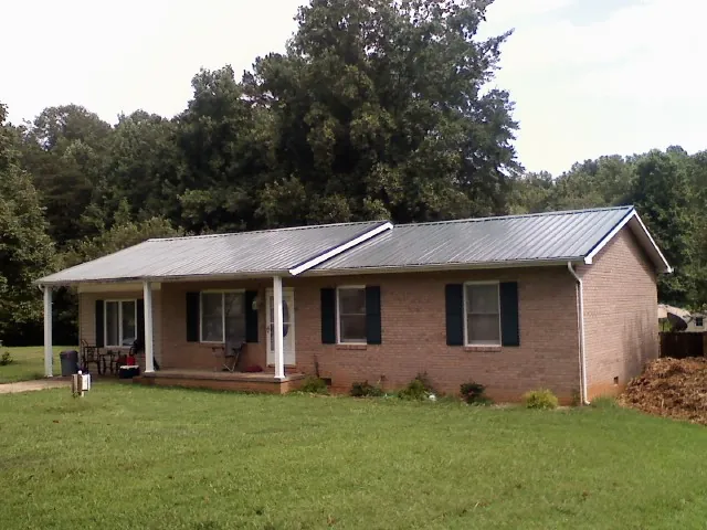 Gray metal roof on a brick ranch house with a side carport in Lodi